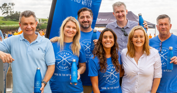 Seven people smiling holding Clean Oceans bottles and wearing Clean Oceans shirts