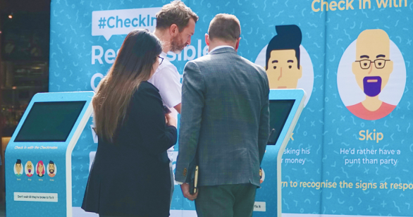 Three people checking out Gamble Aware week installation outside