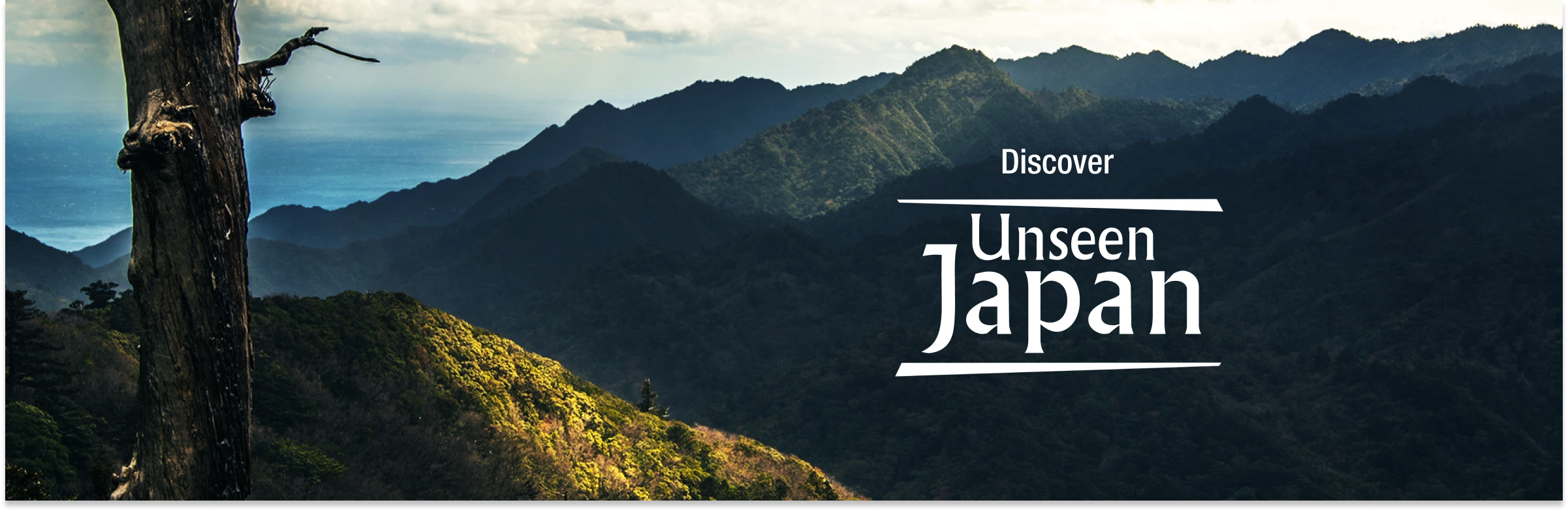 Hero image for the campaign showing a dramatic, sun-drenched mountain range meeting the sea, with the text "Discover Unseen Japan".