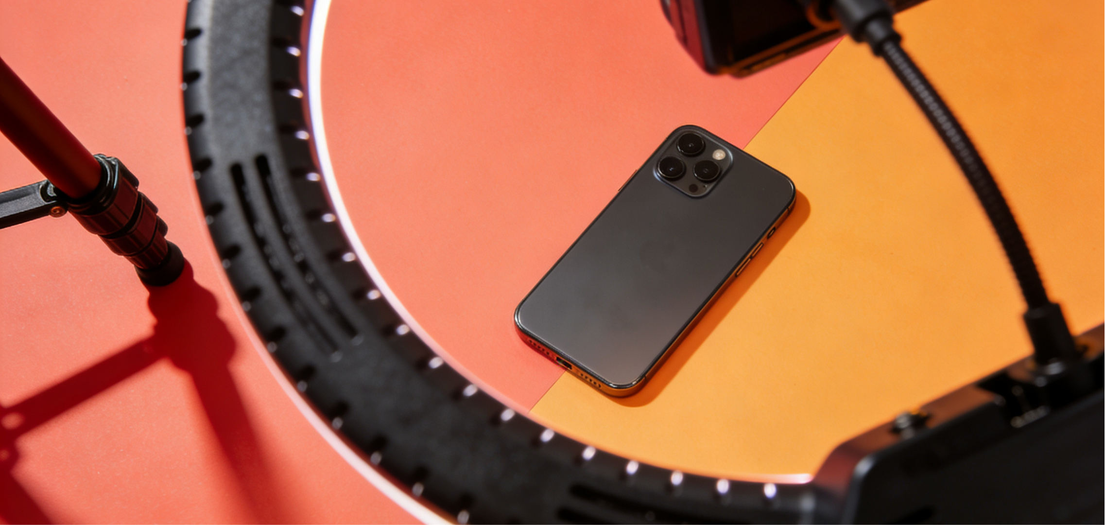 Smartphone placed inside a ring light setup on a colourful orange and red surface, used for social media content creation