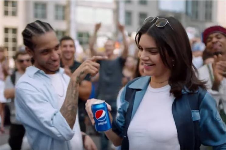 Still from Pepsi's 2017 Jump In advertisement showing Kendall Jenner holding a Pepsi can at a protest march scene